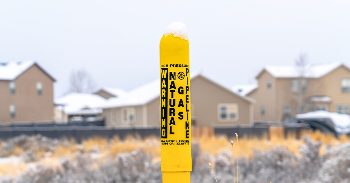 Natural Gas Pipeline Pole in front of a snowy set of houses
